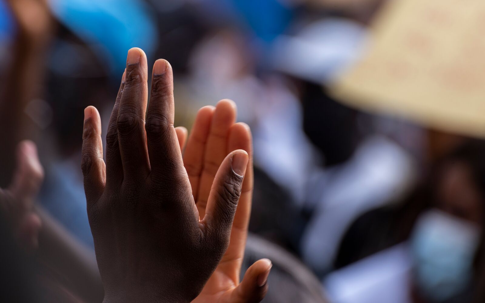 Colored person hands clapping in the middle of a protest against racism, unfocused background